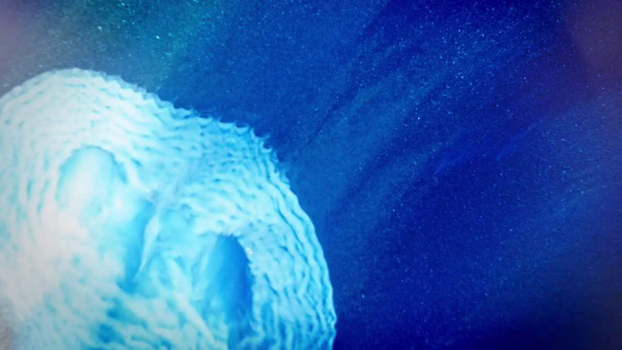 White ink swirling in blue water with a cosmic dust effect resembling a galactic spiral