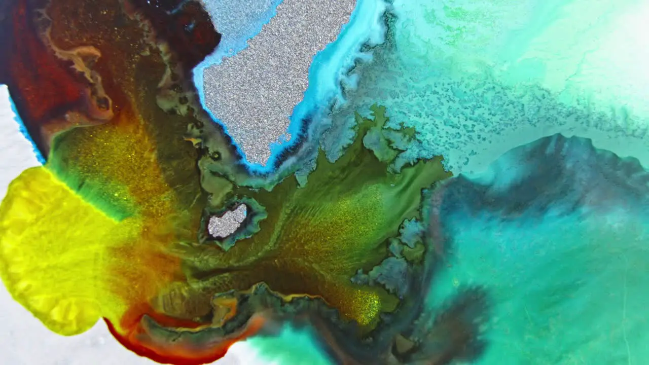 Close-up view of colorful ink in water with glitter creating an abstract organic pattern