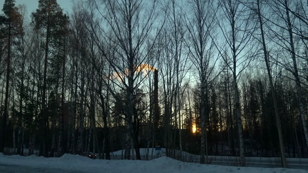 White smoke coming out of a tall chimney during sunset on a cold winter day in Sweden while cars passing by in the foreground