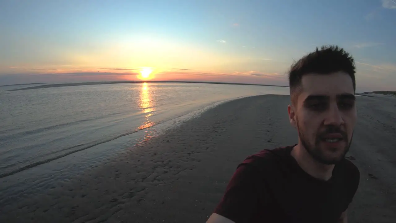 First person man running on the beach with the sunset behind