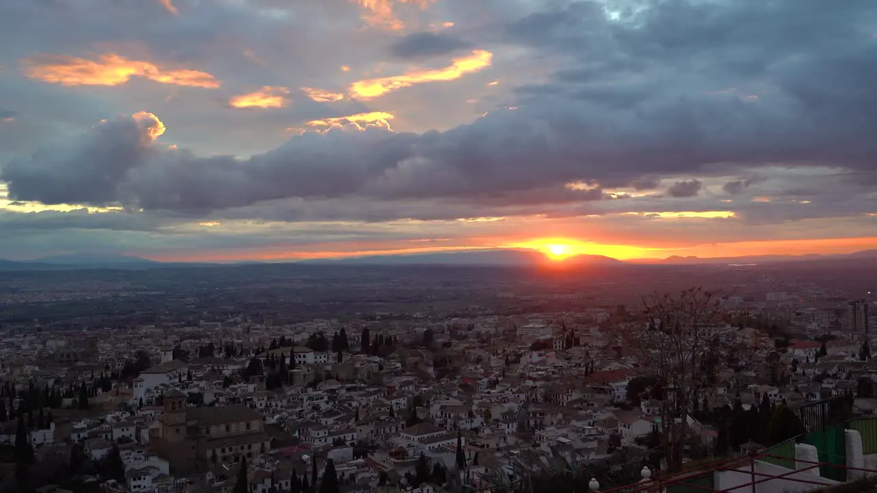 Sun slowly setting behind mountains during vibrant sunrise with cityscape