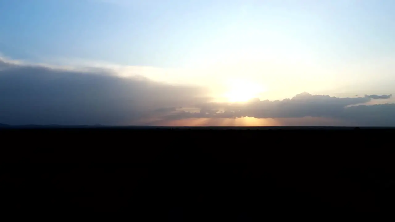 View from inside a jeep driving down a dirt road on a safari trip with a beautiful sunset sky in the background