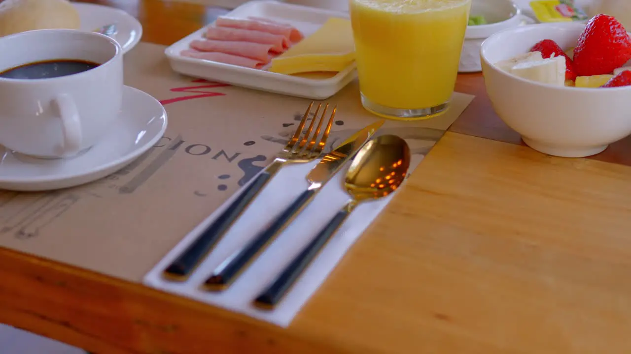 table with breakfast served a knife spoon and fork of bronze color with elegant black stand out