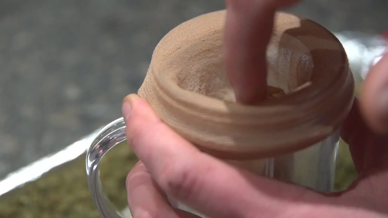 The Cloth Strainer Put In A Small Glass Ready For Extraction Of Marijuana Essential Oil Used For Ailments Close Up Shot