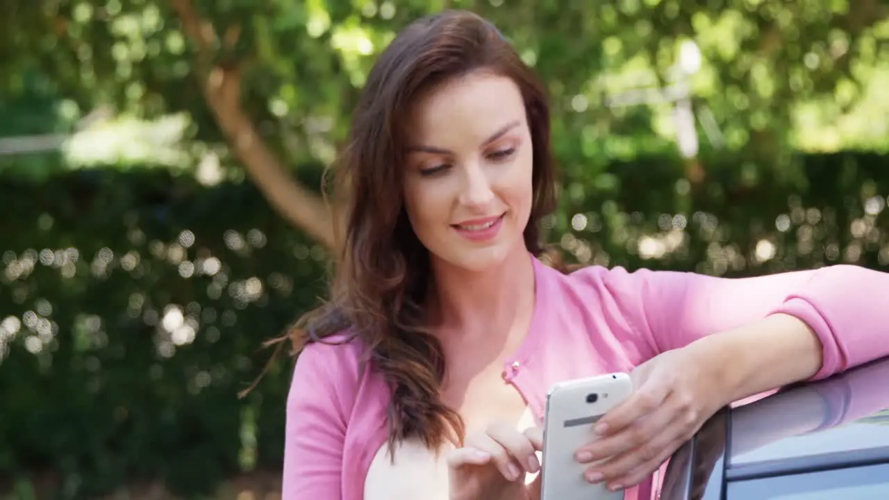 Woman using mobile phone near car