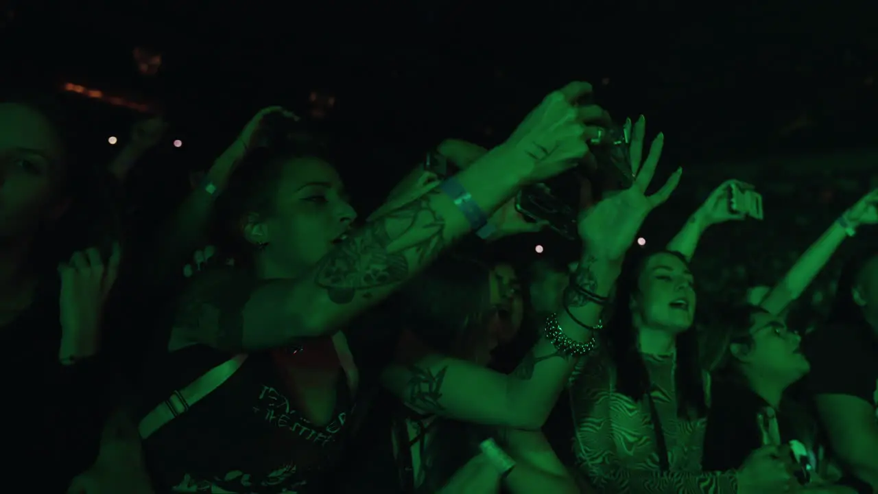 Young Tattooed Woman Lady Holding Cell Phone Filming and Singing During Music Concert Show Audience Crowd Ladies in Arena Filming Music Performance on Stage