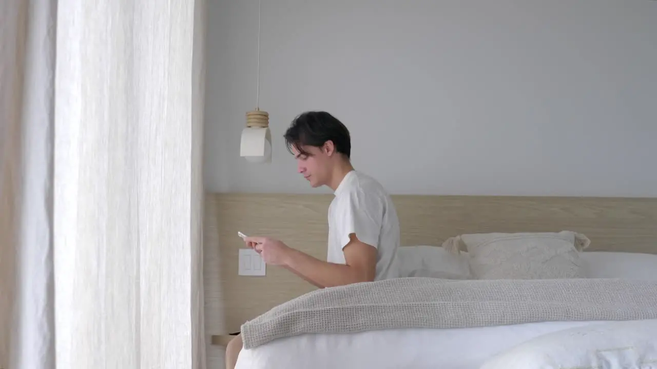 Man Texting On Phone While Sitting On The Bed