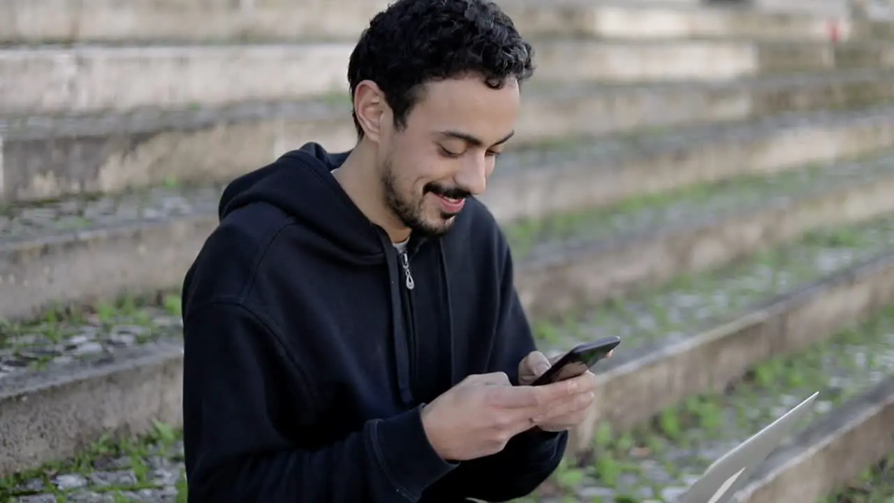 Smiling man using smartphone on street