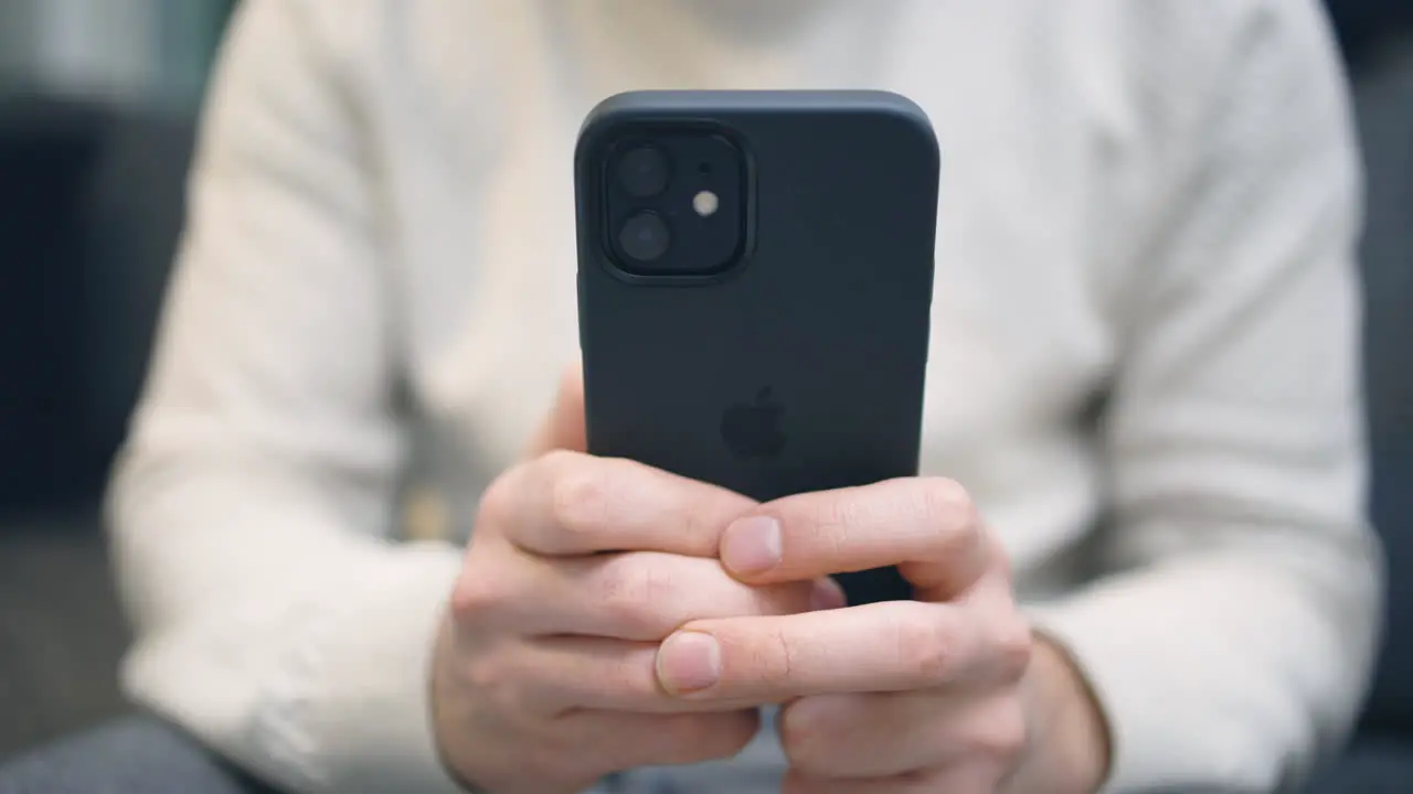 Close-up of back of new dark iPhone being used by white male hands