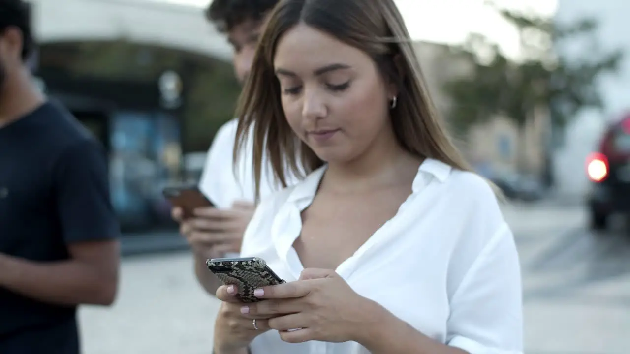 Focused Caucasian woman walking on street with smartphone