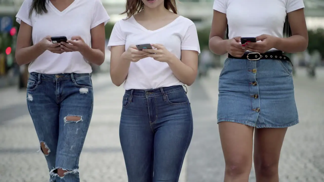 Front view of young women using smartphones during stroll