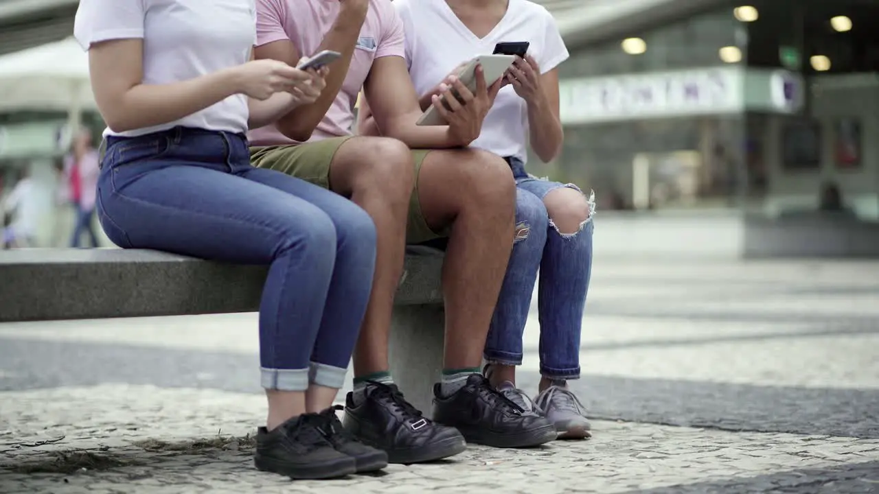 Cropped shot of people sitting on street with digital devices