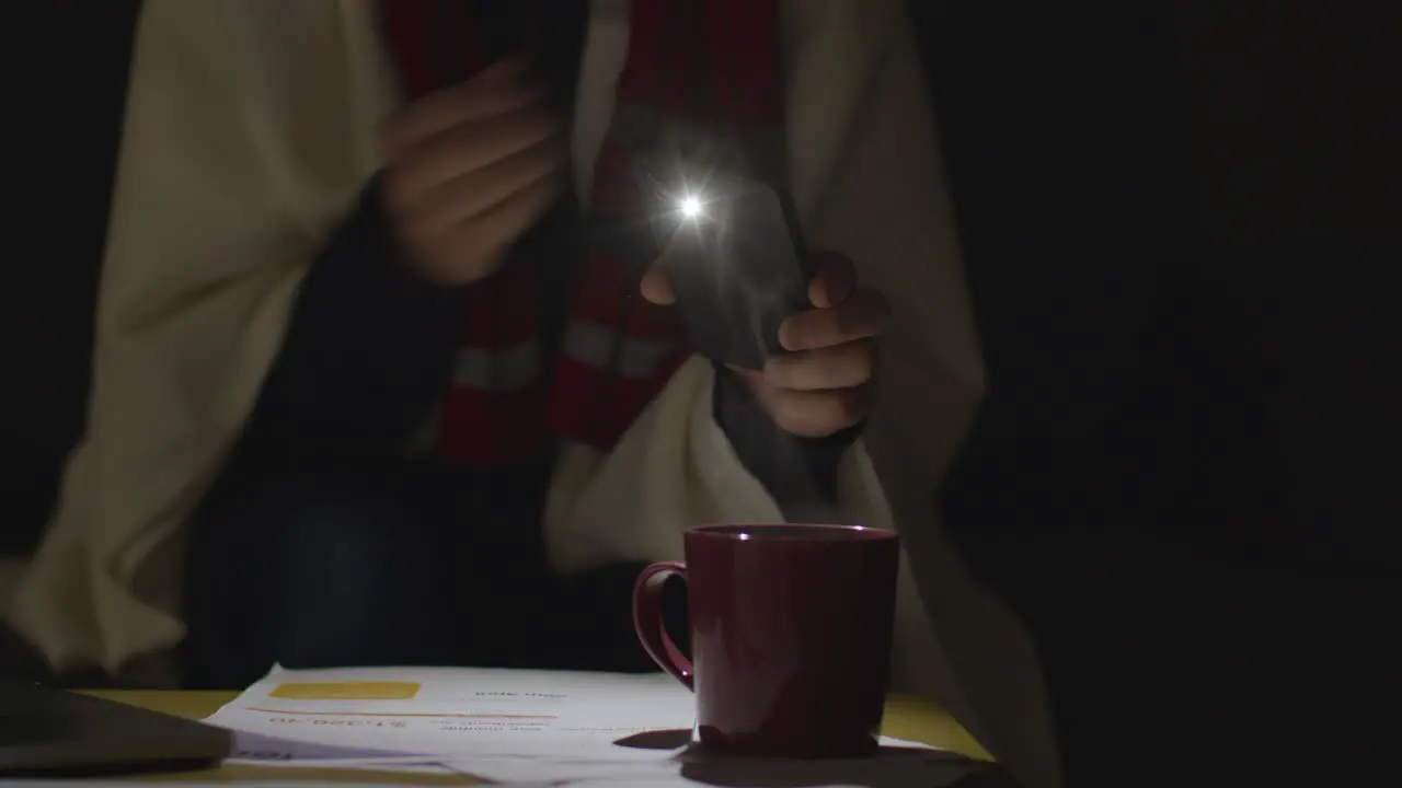 Person Wearing Blanket Sitting On Sofa At Home In Dark When Power Is Cut Off Using Phone Torch 2