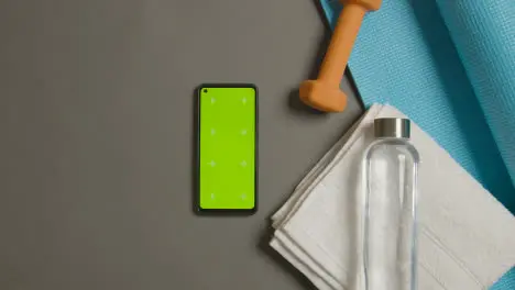 Overhead Fitness Studio Shot Of Male Hand Picking Up And Throwing Down Water Bottle Next To Green Screen Mobile Phone