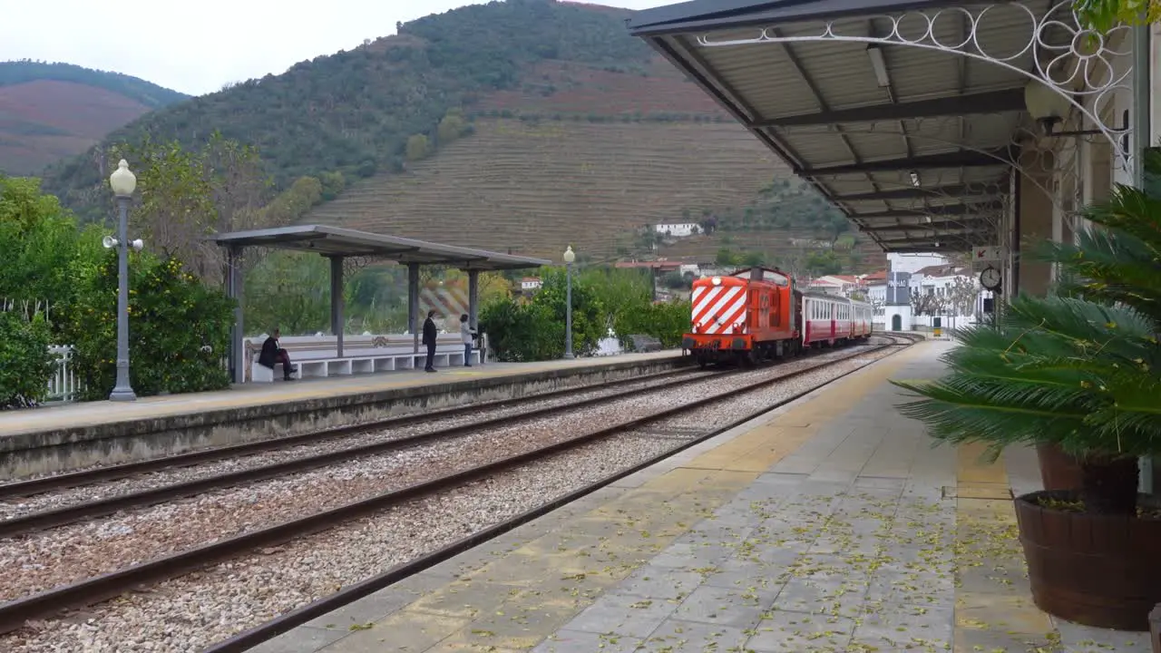 A colorful Portuguese passenger train arrives to a secluded stop in a mountainous region of Portugal Caminhos de Ferro Portugueses