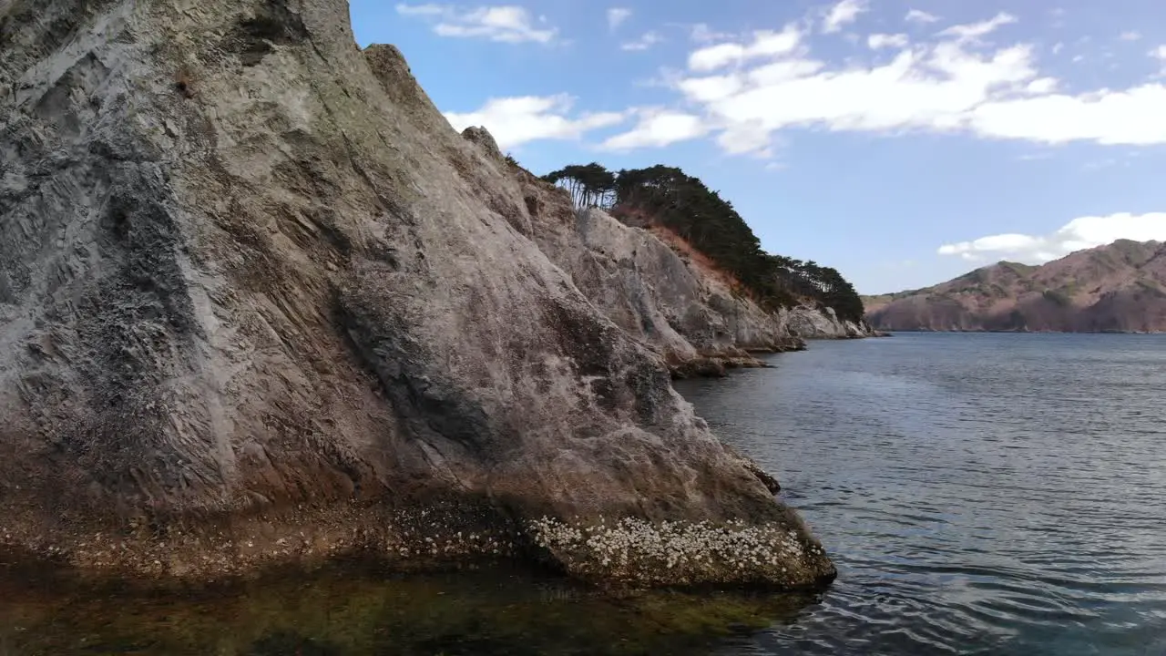 Slow aerial sideways reveal of beautiful rocks at Jodagahama beach in Japan