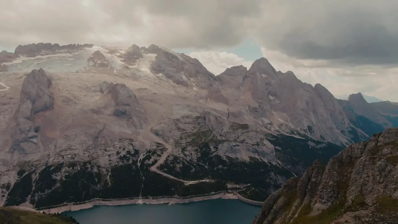 Flying towards a glacier over a mountain ridge on a cloudy summer day steep tall mountains cinematic grade