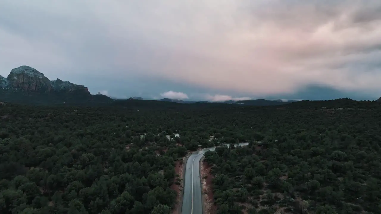 Car Driving On Road In Picturesque Sedona Arizona Landscape On A Cloudy Day aerial drone shot