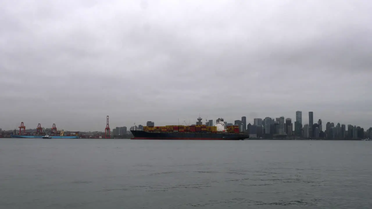 Boats Sailing At Vancouver Harbour Passing By A Container Ship Anchored At The Port On A Cloudy Day In Canada wide shot time lapse