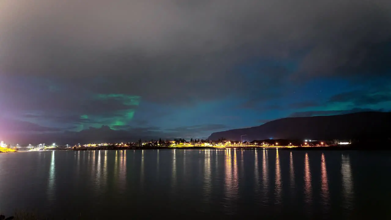 Cloudy Night Sky Timelapse Of Aurora Borealis By The Lake In Iceland wide shot