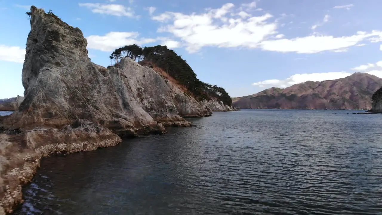 Low aerial drone flight forward over ocean and tall cliffs on clear day