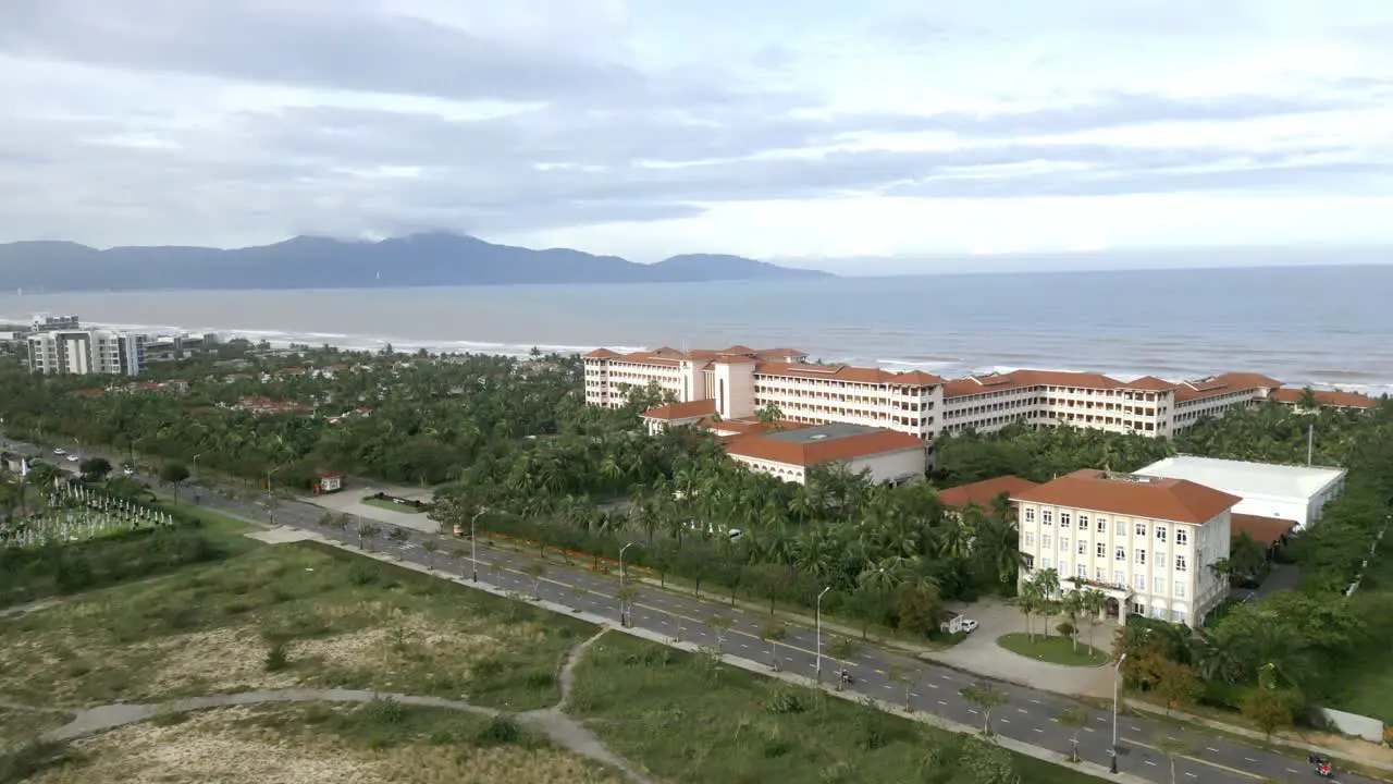 Flyover from the mountains to Ha My Beach on a cloudy day with wave hitting the shore