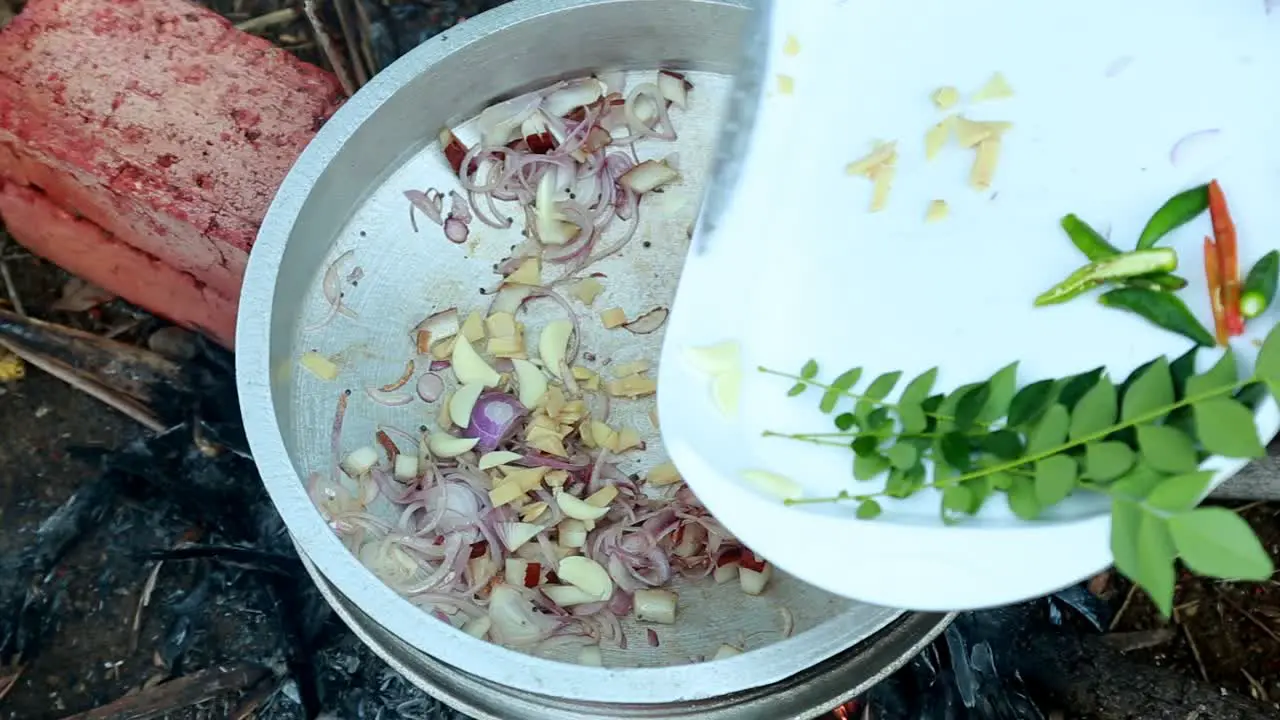 Ginger green chillies garlic and curry leaves are added to the chopped onion  black clam masala curry traditional outdoor black clams cooking pollution  masala  brick