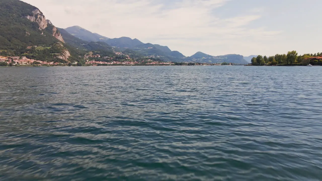 Cinematic Flight Over The Blue Water Of Lake Como In Italy With Mountains And Cloudy Sky In Background aerial drone shot