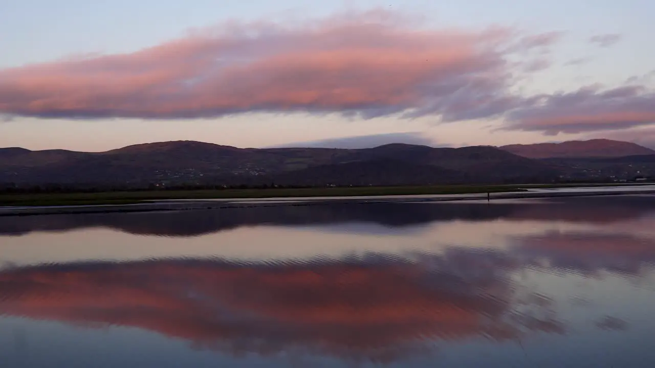 Beautiful view in the evening from the shore on the water and the clouds reflected in the water in the distance you can see the mountains