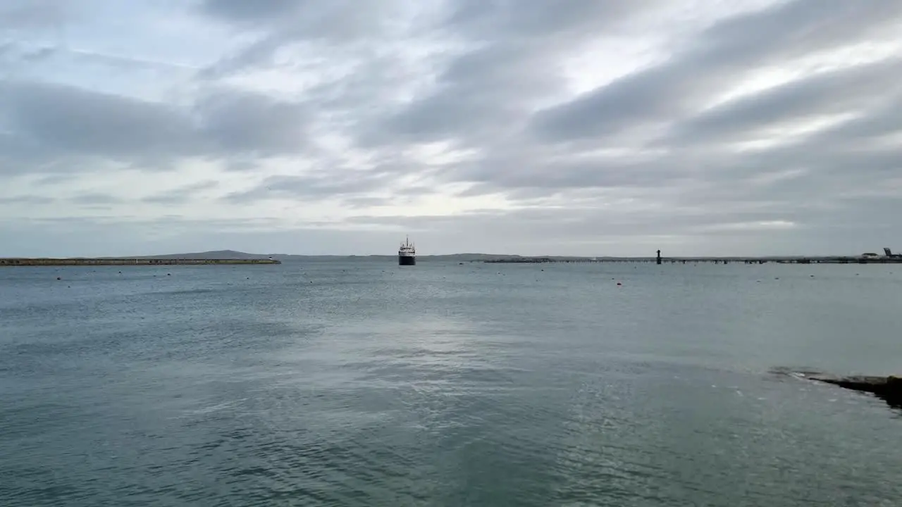 Holyhead seascape industrial dredger ship entering calm overcast breakwater harbour