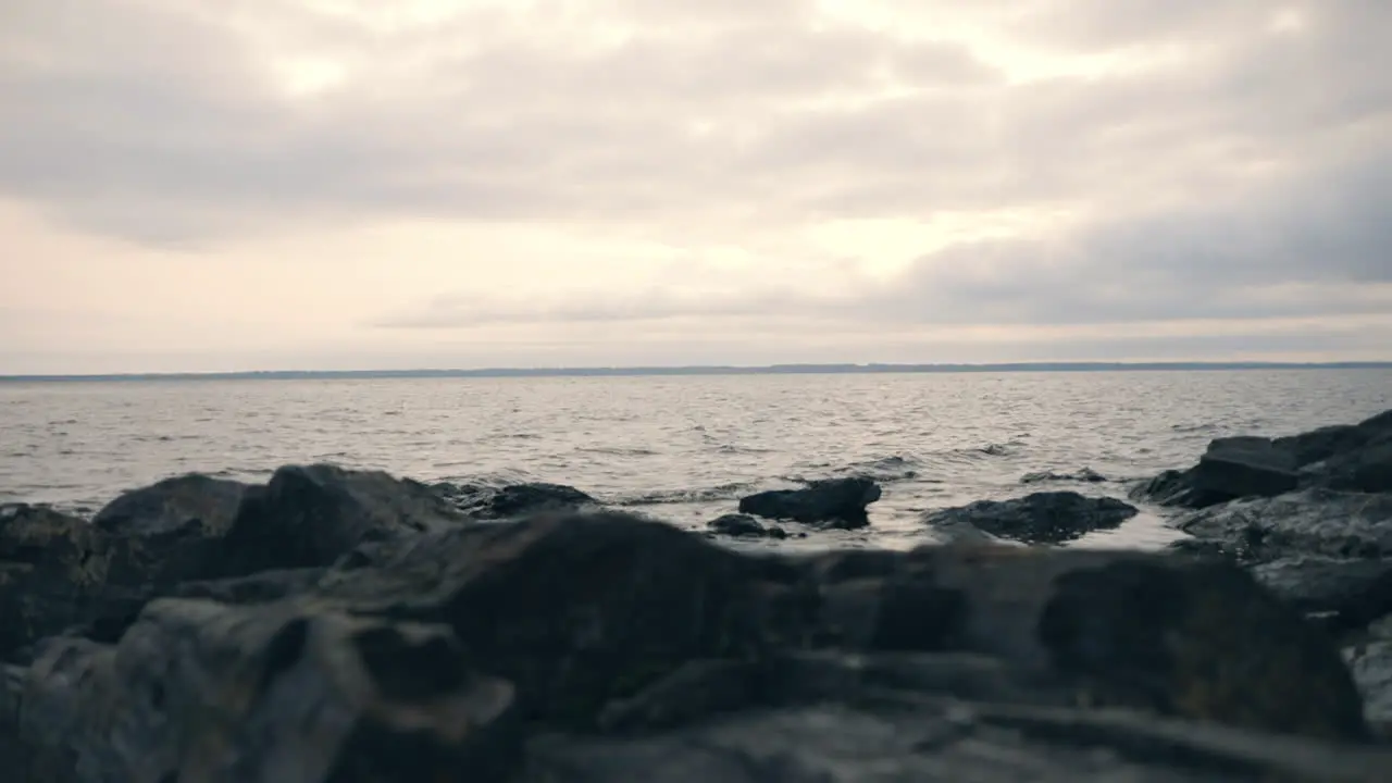 Low angle view of small waves hitting cliffs on a rocky shore on a moody cloudy autumn day in Finland