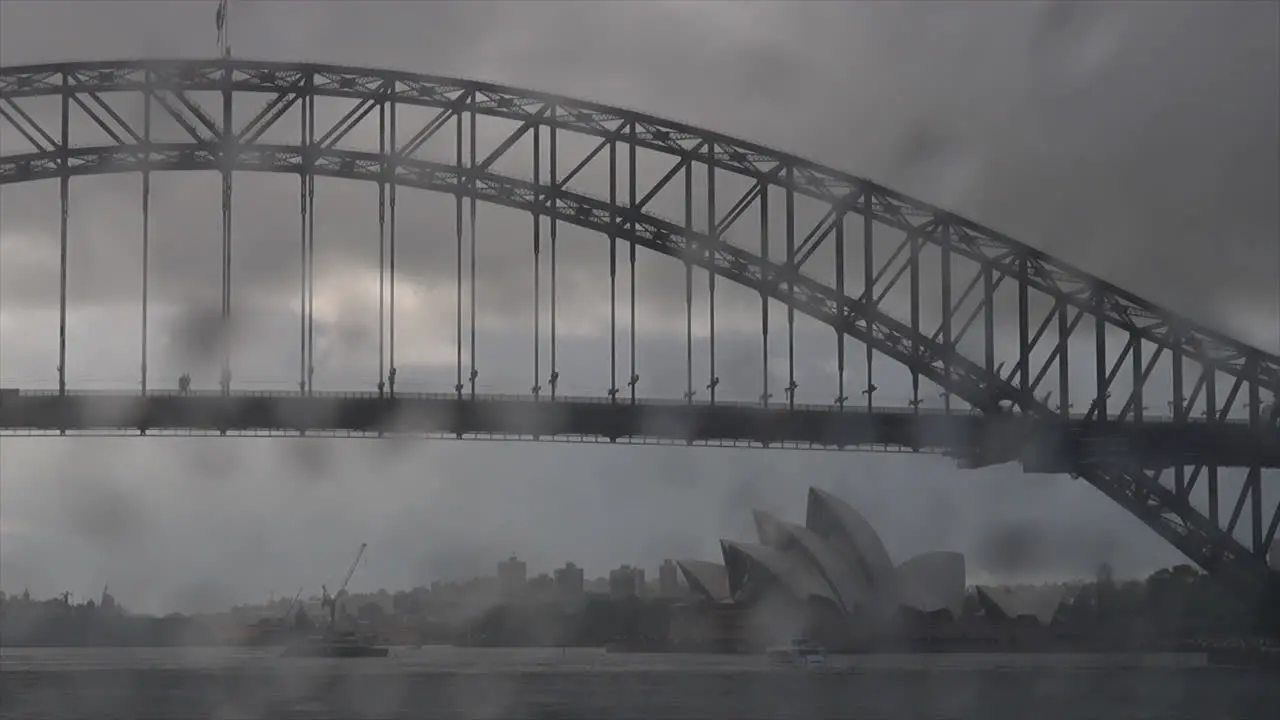 Raindrops hitting the windscreen of a car with Sydney Opera house out of focus in the background