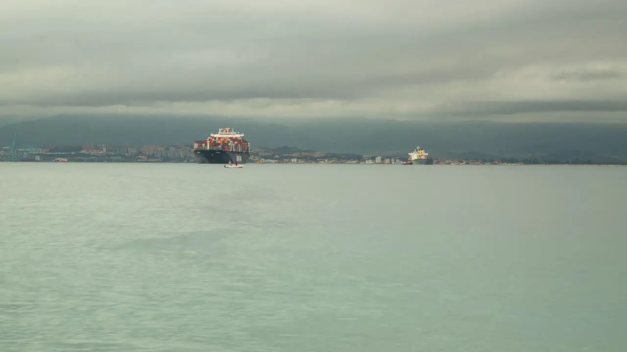 Container vessel moored near Gibraltar harbor time lapse view with stormy clouds