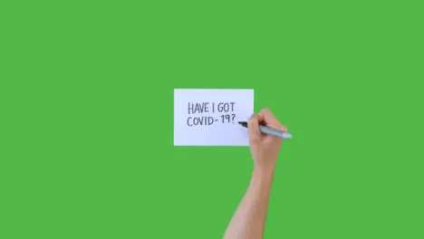 Woman Writing Have I Got Covid 19 on Paper with Green Screen