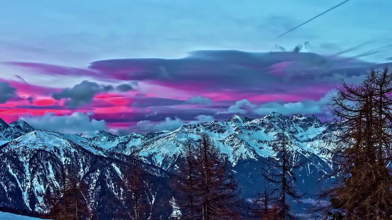 Colorful pink sunrise beyond the rugged mountain peaks of the Alps time lapse