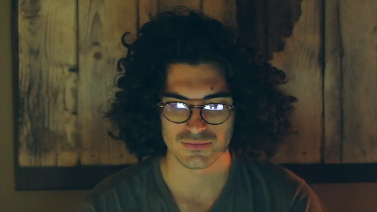 Serious Man with Glasses Focused on Screen in Home Office at Night