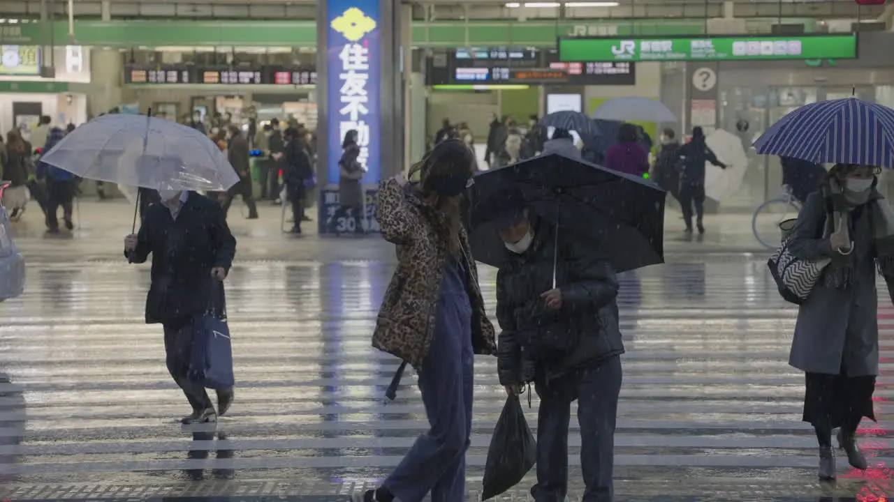 People Rushing To Cross The Road Outside The Shinjuku JR Station During Snowing In City Of Tokyo Japan