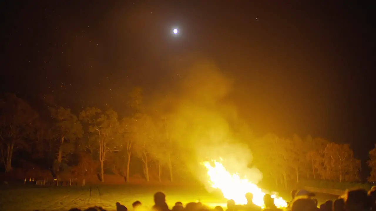 Night Time Large Campfire Outside With Sillhoute Of Crowds