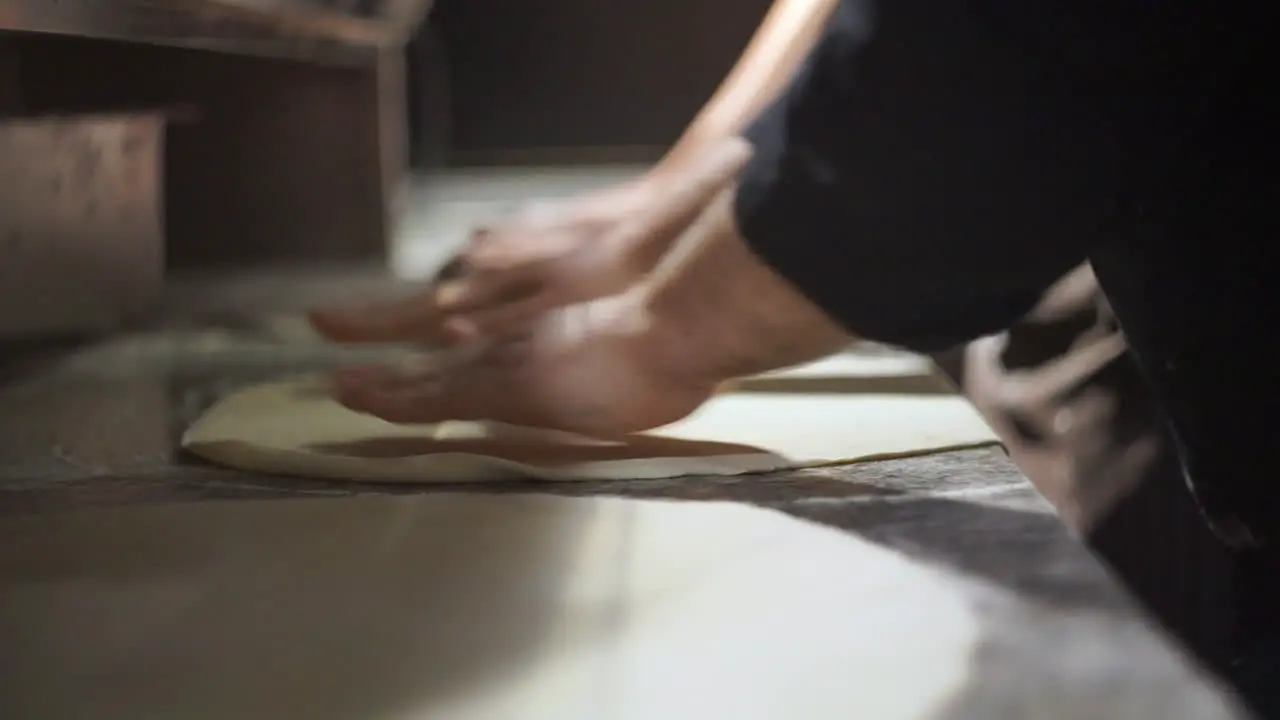 A cook prepares pizza on a marble bench