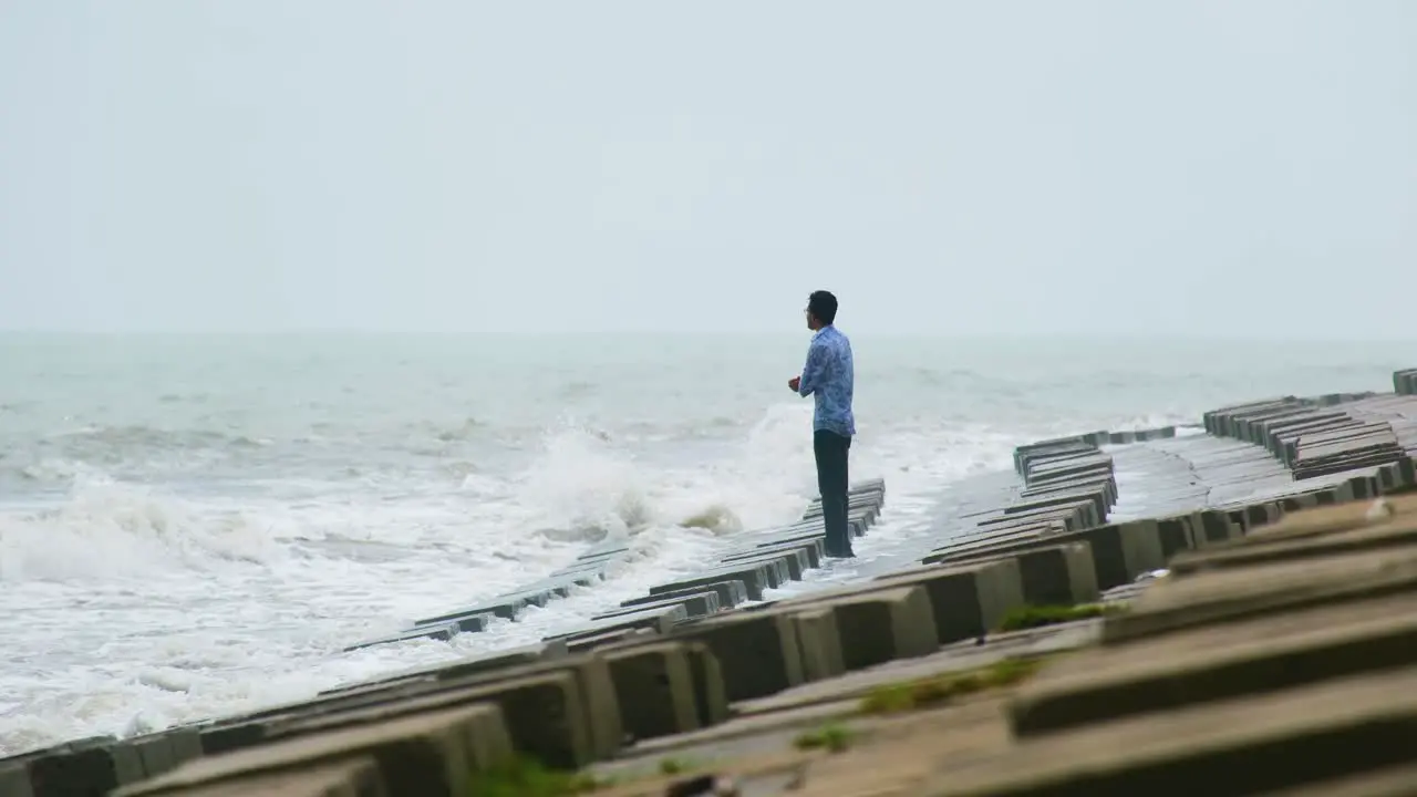 Thoughtful man standing in a dam and staring at the ocean