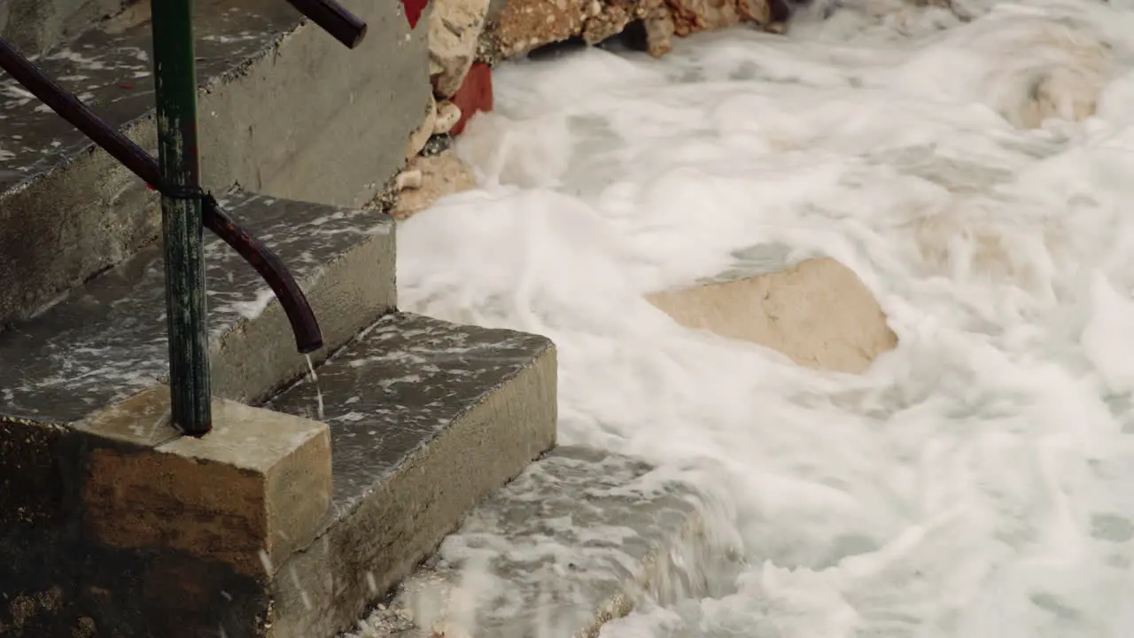 Ocean waves crash on exposed concrete slabs eroded away from water exposure