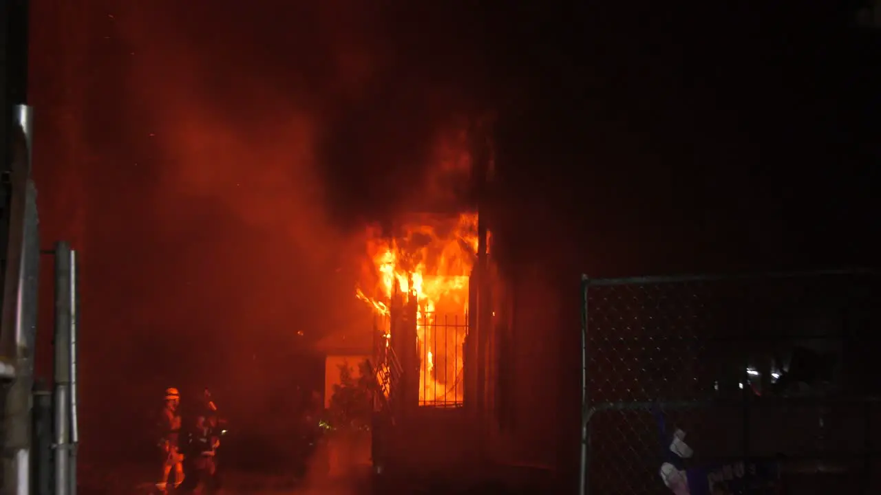 Firefighters extinguishing a house in flames structure fire nighttime in LA USA