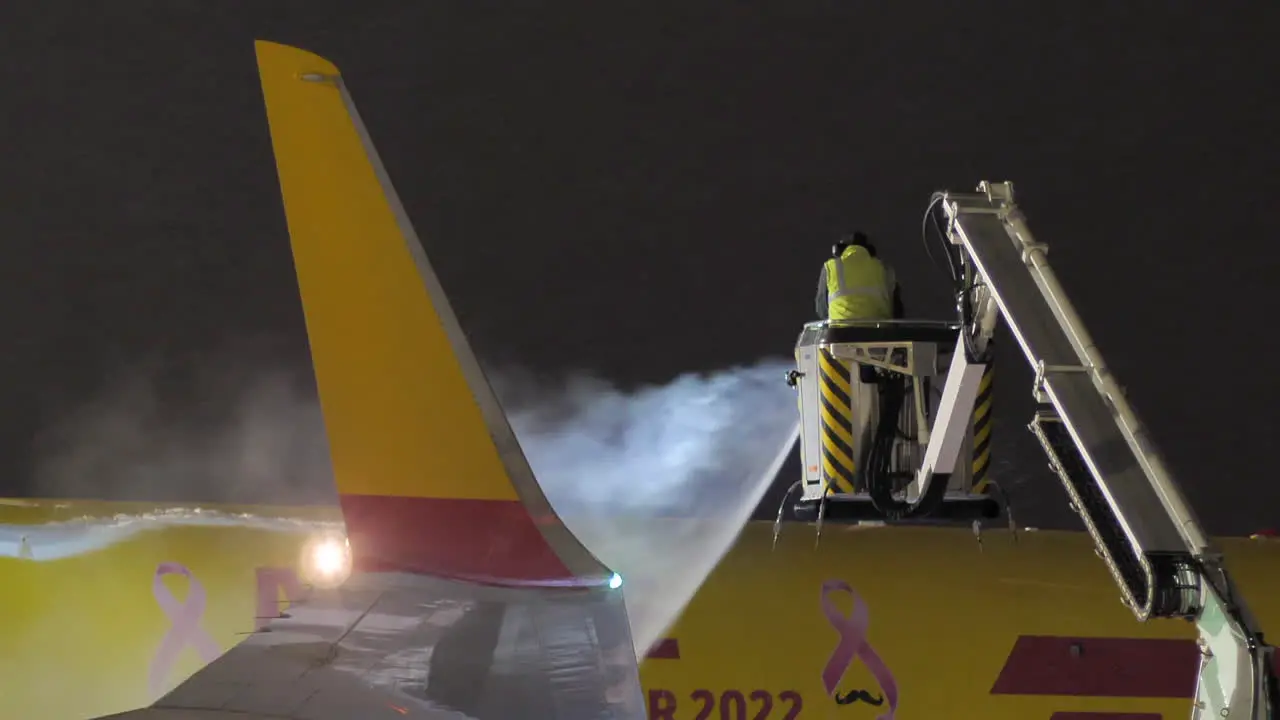 Brno airport support staff employee deicing DHL plane at night