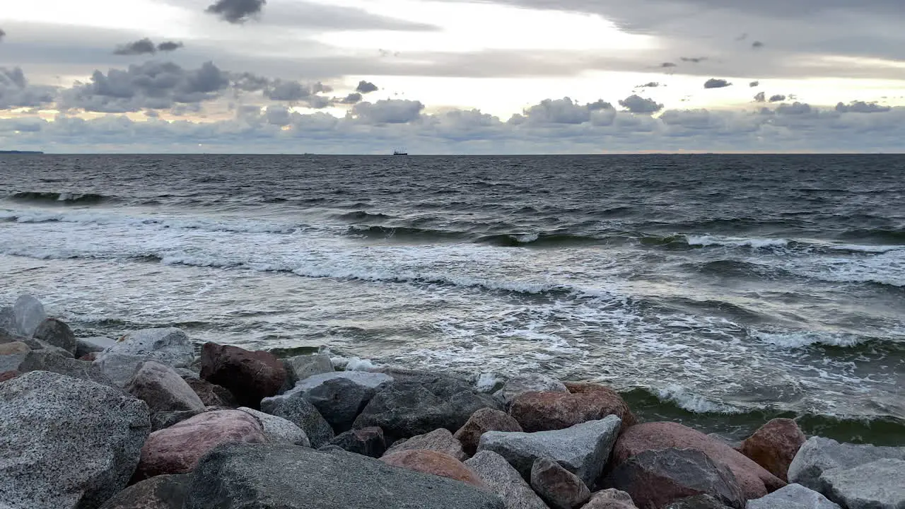 Cloudscape Over The Splashing Waves Of The Ocean At The Rocky Coastline Through Dusk