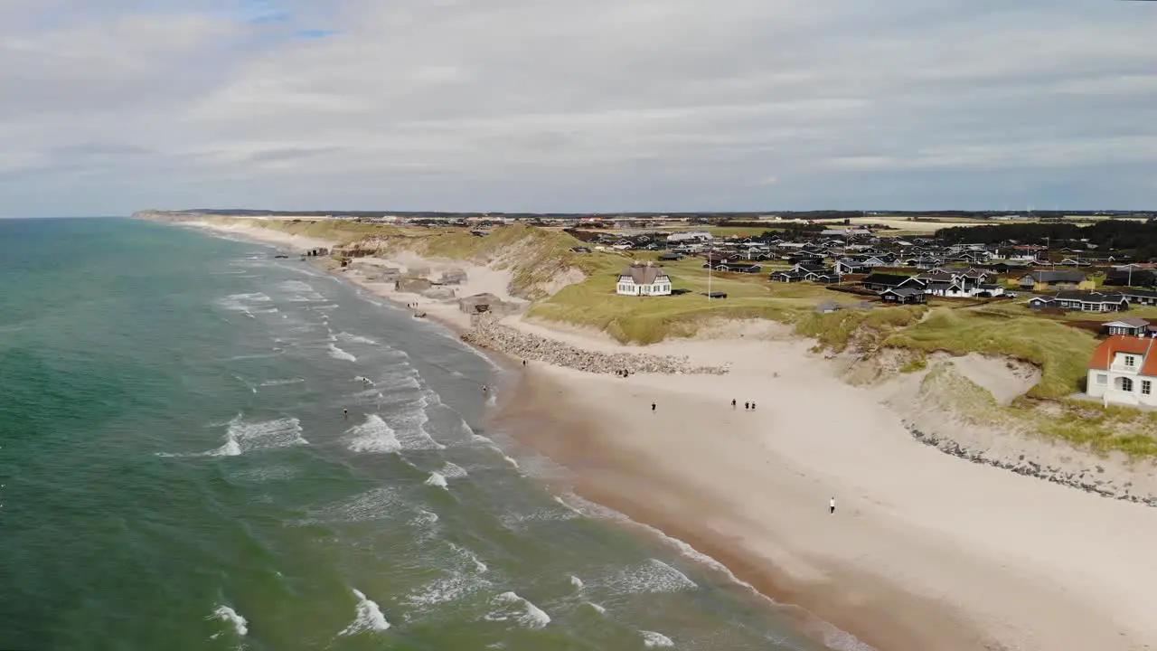 Aerial of the beautiful Danish west coast with white sand beaches and beautiful waves and and old house in front of some old German bunkers