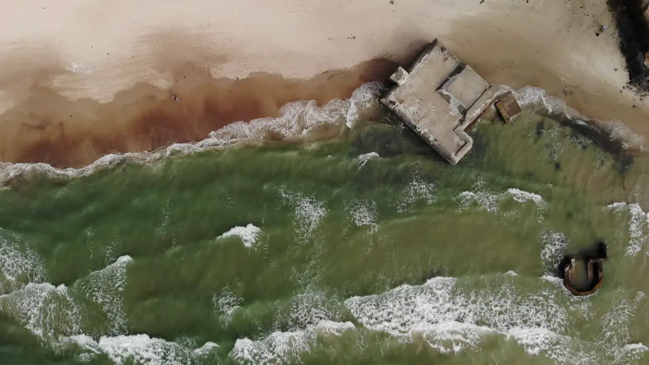 Aerial top down view of waves crashing against old German bunkers from world war 2 located on a beach on at the Danish west coast