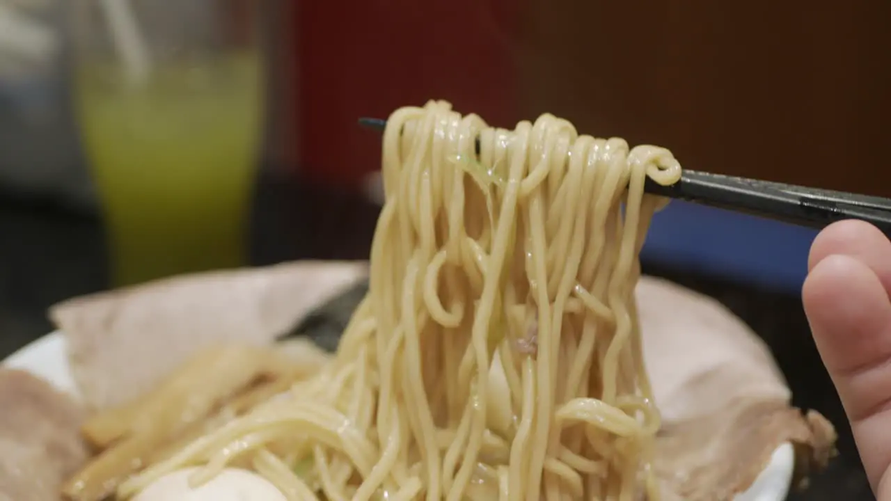 man use chocpstick to eat ramen japanese noodle