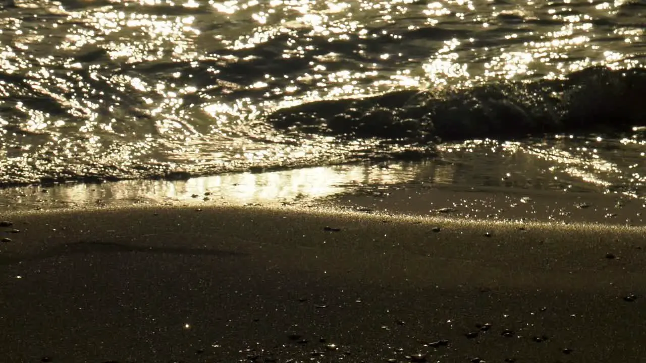 Slow motion waves on sand at dawn close up abstract