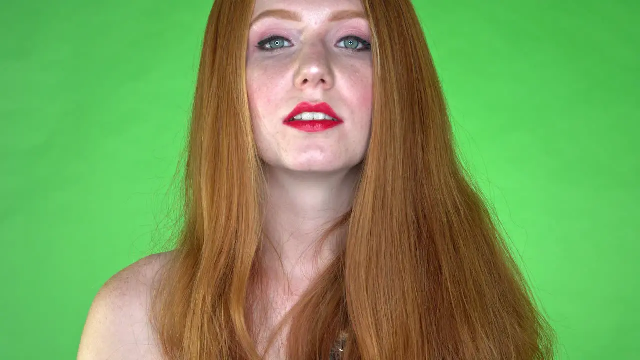 A close-up of a woman's face showing neutral expression on a seamless green studio background-green screen