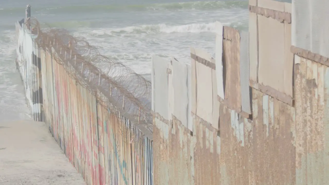 Tijuana beach border line with sea crashing waves